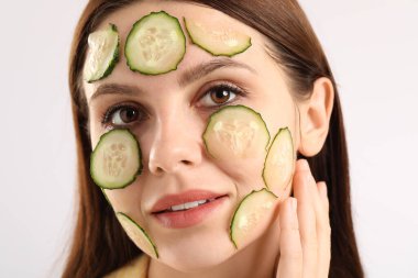 Beyaz arka planda salatalık dilimleri olan bir kadın.