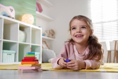 Mutlu küçük kız oyun odasında yerde yatıyor.