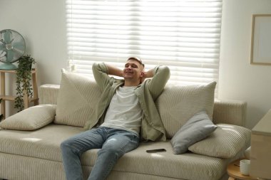 Evdeki kanepede dinlenen genç adam.