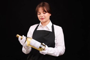 Siyah arka planda beyaz şarap şişesi olan profesyonel şarap garsonu.