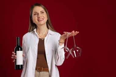 Kırmızı arka planda şarap ve gözlüklü profesyonel şarap garsonu.