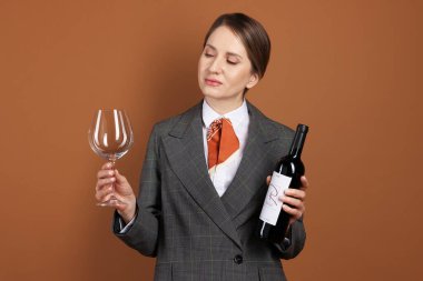 Kahverengi arka planda cam ve şarap şişesi olan profesyonel şarap garsonu.