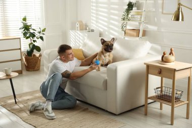 Evdeki kanepenin yanında tatlı köpeği ve oyuncağıyla rahatlayan genç bir adam.