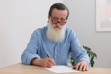 Ahşap masada son dilek ve vasiyetnameyi imzalayan kıdemli bir adam.