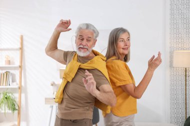 Mutlu yaşlı çift evde dans ediyor.