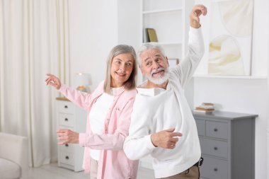 Mutlu yaşlı çift evde dans ediyor.