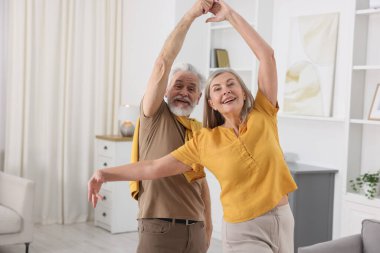 Mutlu yaşlı çift evde dans ediyor.
