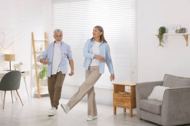 Mutlu yaşlı çift evde dans ediyor.