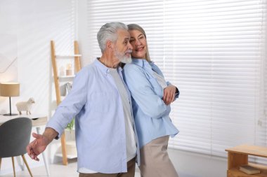 Mutlu yaşlı çift evde dans ediyor.