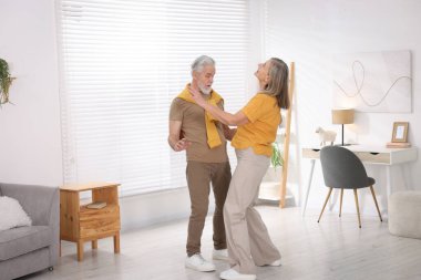 Mutlu yaşlı çift evde dans ediyor.