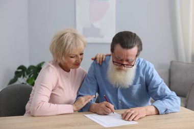 Ahşap masada son arzuları ve vasiyetnameleri imzalayan yaşlı çift.