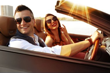 Güneşli bir günde üstü açık lüks bir arabada şık bir çift.