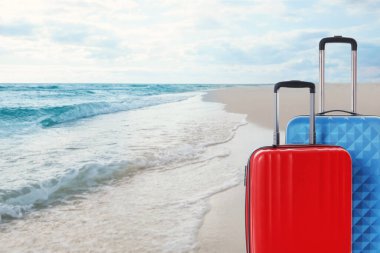 Okyanus kıyısındaki sahilde iki bavul. Tatil gezisi