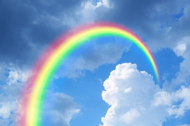 Parlak renkli gökkuşağı ve mavi gökyüzündeki bulutlar