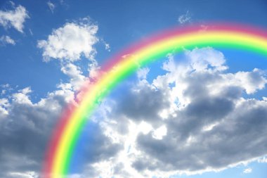 Parlak renkli gökkuşağı ve mavi gökyüzündeki bulutlar