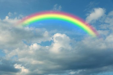 Parlak renkli gökkuşağı ve mavi gökyüzündeki bulutlar