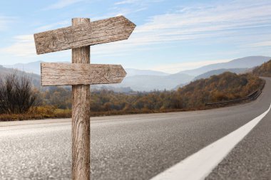 Dağ yolunda farklı yönlere bakan okları olan tahta işaret direği.