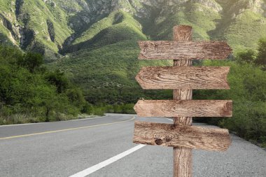 Dağ yolunda farklı yönlere bakan okları olan tahta işaret direği.