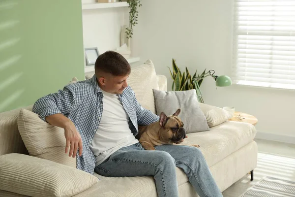 Evdeki kanepede dinlenen sevimli köpeğiyle genç bir adam.