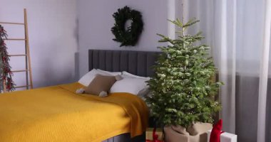 Güzel Noel ağacı, hediyeler, köknar çelengi ve rahat bir yatak, kamera içeri giriyor.