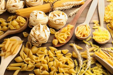 Farklı türde çiğ makarna ve çiviler tahta masanın üstünde.