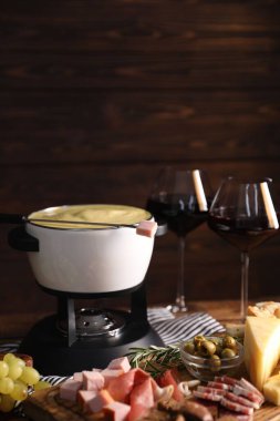 Lezzetli eritilmiş peynirli fondü, abur cuburlar ve ahşap masada şarap. Metin için boşluk