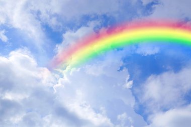 Parlak renkli gökkuşağı ve mavi gökyüzündeki bulutlar