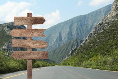 Dağ yolunda farklı yönlere bakan okları olan tahta işaret direği.