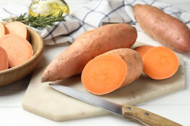 Çiğ patates ve bıçak beyaz ahşap masada, yakın plan.