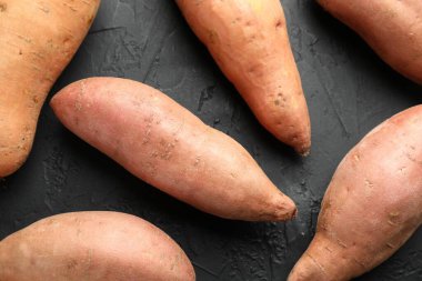 Siyah desenli masada çiğ patates, düz uzanmış.