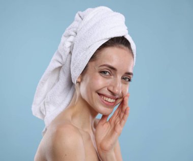 Açık mavi arka planda havluya sarılı güzel bir kadın, mesaj için yer var.