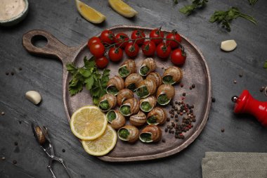 Gri masada servis edilen lezzetli pişmiş salyangozlar.