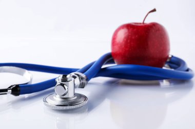 Olgun elma ve steteskop beyaz masada, yakın plan.
