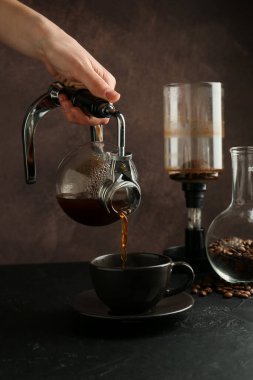 Siyahların masasındaki kahve makinesinden kahve dolduran kadın, yakın plan.