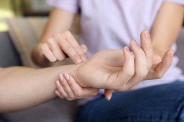 Kadın adamın nabzını kontrol ediyor. Parmakları evde, yakın plan.