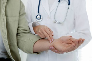 Doktor klinikte adamın nabzını kontrol ediyor.