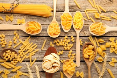 Farklı türde çiğ makarnalar, kaşık ve çiviler, tahta masa, düz yatış