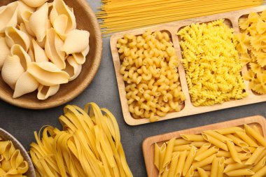 Gri masada farklı türde çiğ makarna, düz yatıyordu.