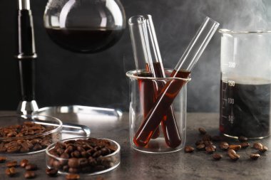 Kahve, fasulye ve labaratuar camlı elektrikli süpürge gri masada, yakın plan.