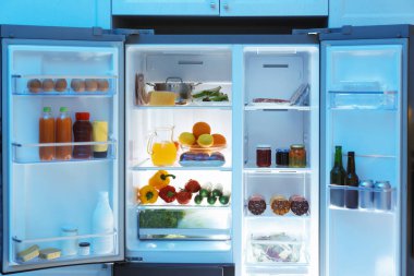 Mutfakta farklı taze gıda ürünleri olan modern buzdolabı.