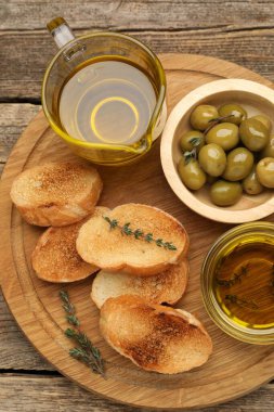 Tahta masa üzerinde baget, yağ, zeytin ve kekik dilimleri.