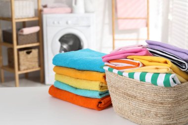 Çamaşır sepetinin içinde giysiler ve havlular beyaz masa içinde, yakın plan.