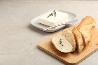 Tereyağlı baget ekmek, kekik ve bıçak gri desenli masa, yakın plan. Metin için boşluk