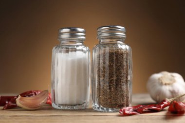 Ahşap masa üzerinde baharatlı tuzluk ve biber karıştırıcılar kahverengi eğimli arka plan, yakın çekim