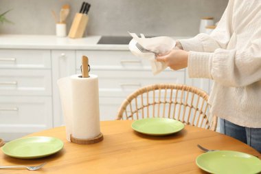 Mutfaktaki tahta masada çatalı kağıt havluyla silen kadın, yakın plan.