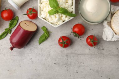 Farklı taze süt ürünleri, domates ve fesleğen, gri desenli masa, düz yatak. Metin için boşluk