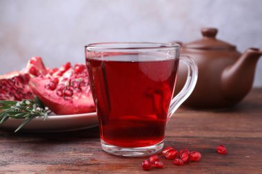 Aromatik nar çayı, taze meyve ve biberiye ahşap masada, yakın plan.