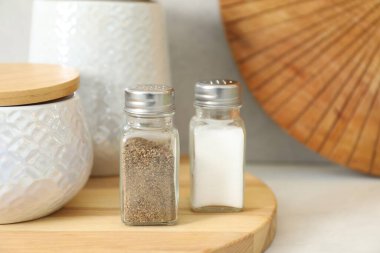 Beyaz masadaki baharatlı tuzluklar ve biberlikler, yakın plan.