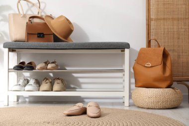 Beyaz duvarın yanında farklı ayakkabı ve aksesuarlarla dolu bir ayakkabı deposu.