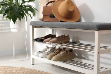 Farklı ayakkabılar, aksesuarlar ve beyaz duvarın yanındaki ev bitkileriyle ayakkabı deposu, yakın plan.